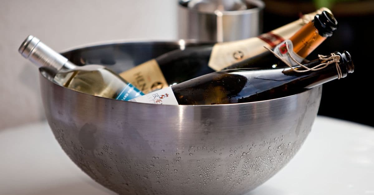 A selection of chilled wine bottles in a stainless steel bowl creates an elegant indoor display.