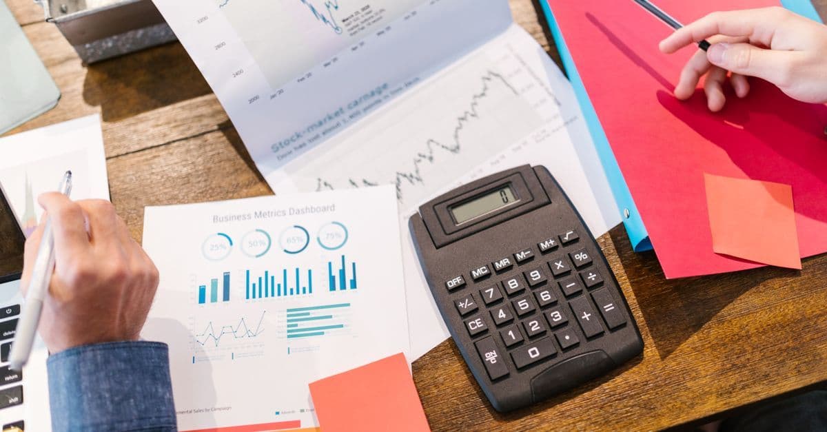 Finanzunterlagen mit Diagrammen und Taschenrechner auf einem Tisch für Analyse und Planung