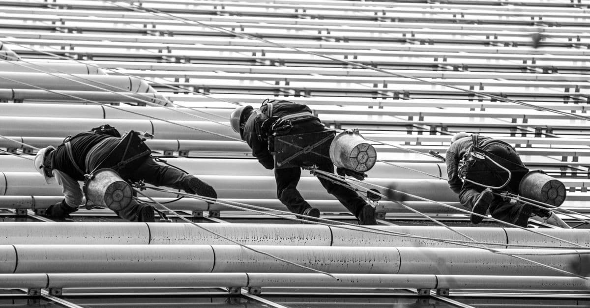 Monochrome image of workers climbing a steel structure showcasing urban life and industry in Buenos Aires.