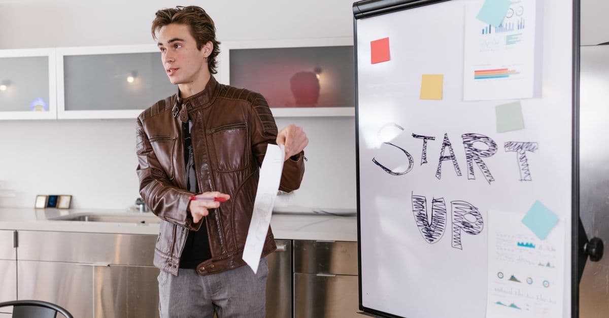 Junger Unternehmer präsentiert drinnen Start-up-Strategien an einem Flipchart.