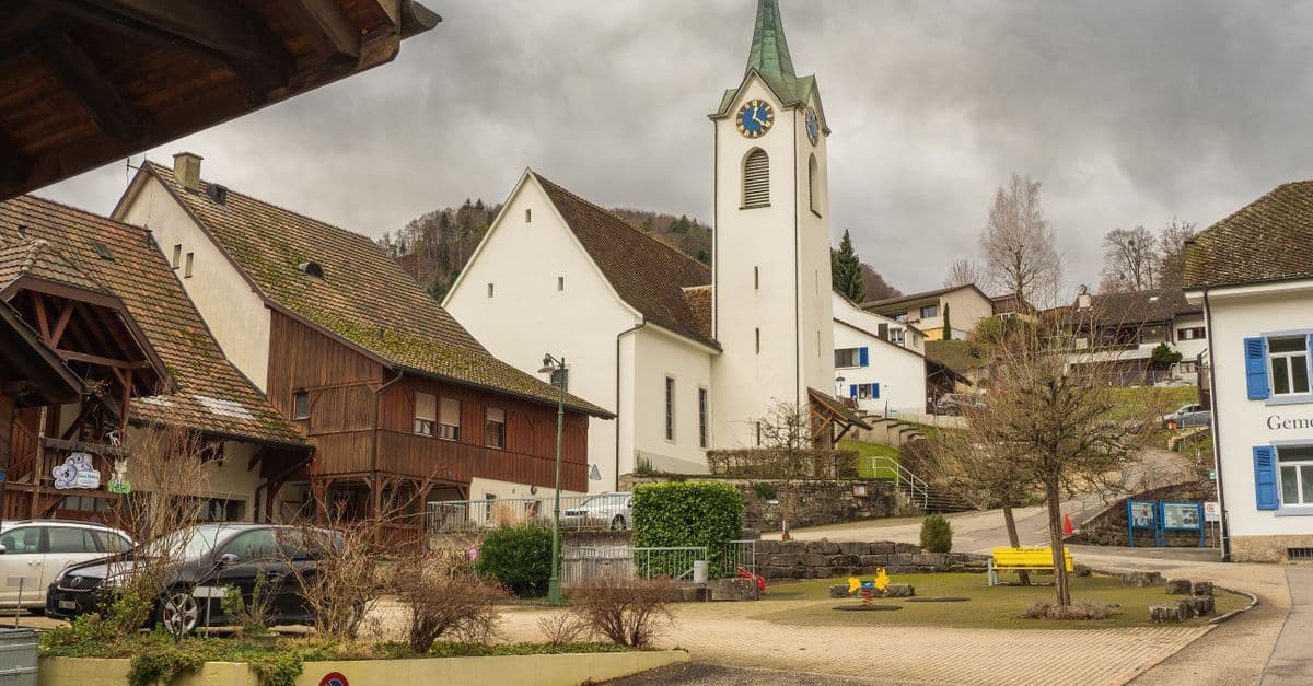 Charming village scene featuring a historic church tower under overcast skies.