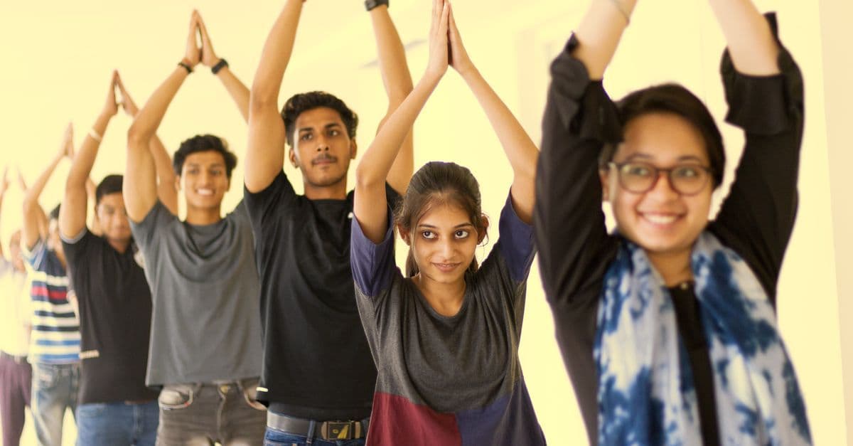 Gruppe junger Erwachsener übt konzentriert und begeistert Yoga in einem Kurs.