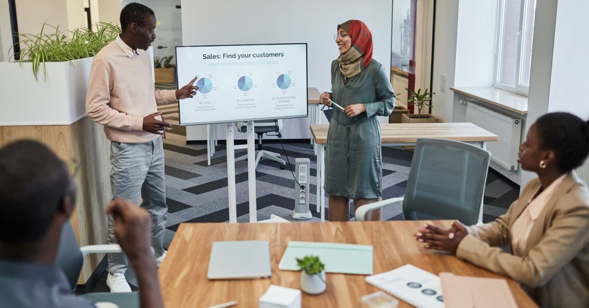 A diverse team engaging in a business meeting focused on sales strategy with visual aids.
