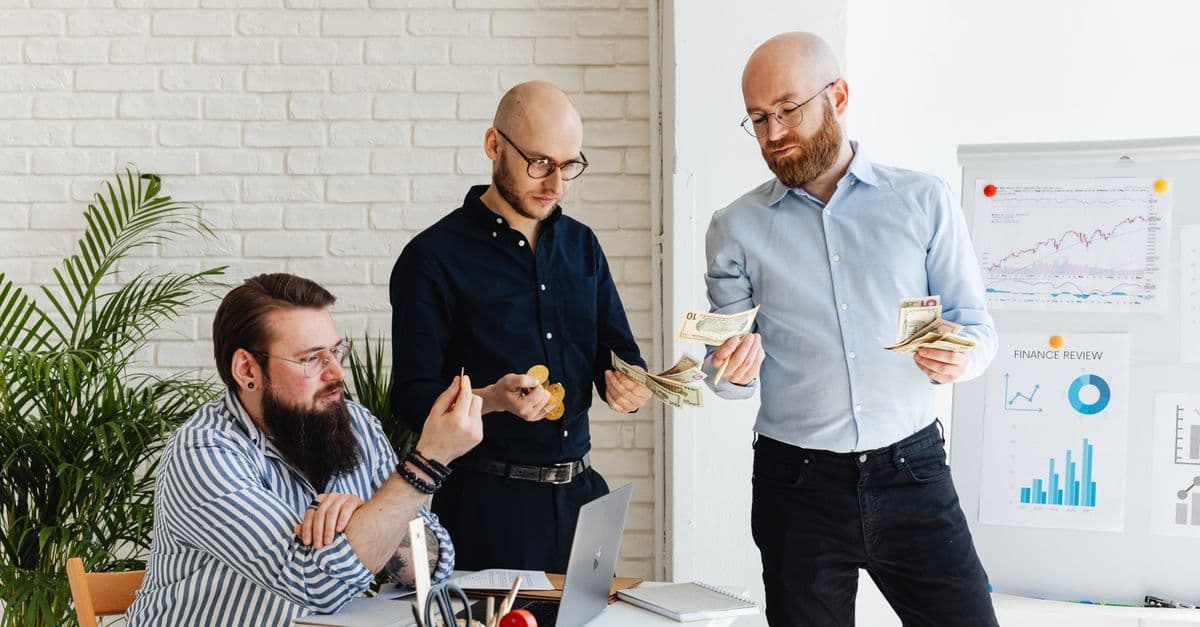 Drei Geschäftskollegen besprechen Finanzstrategien und prüfen Diagramme in einem modernen Büro.
