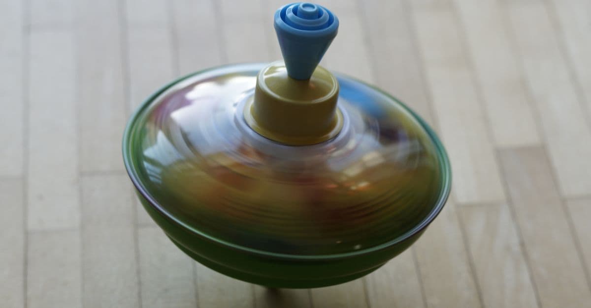 Colorful spinning top captured in motion on a wooden floor, showcasing vivid dynamics.