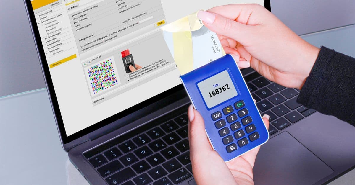 Hands using a TAN generator next to a laptop for secure online banking transactions.