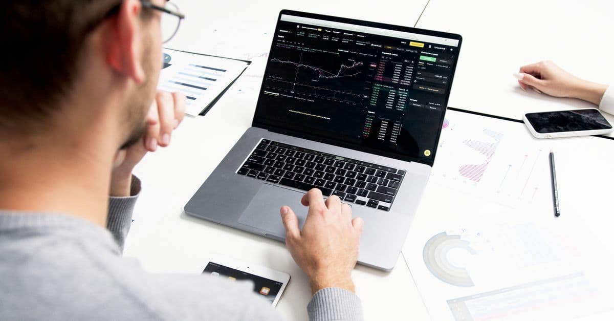 Business professional analyzing stock market data on a laptop for investment insights.