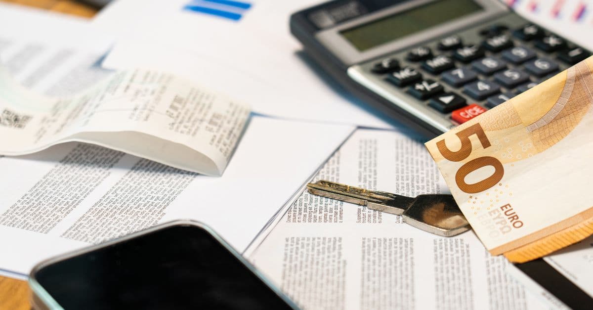 Flat lay of financial documents, euro note, calculator, smartphone, and key for budget management.