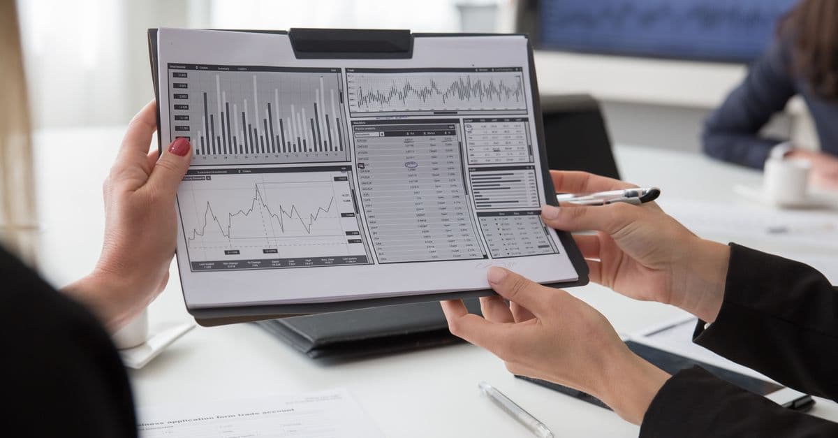 Mehrere Fachleute prüfen Papierausdrucke mit Datencharts in einer Besprechung.