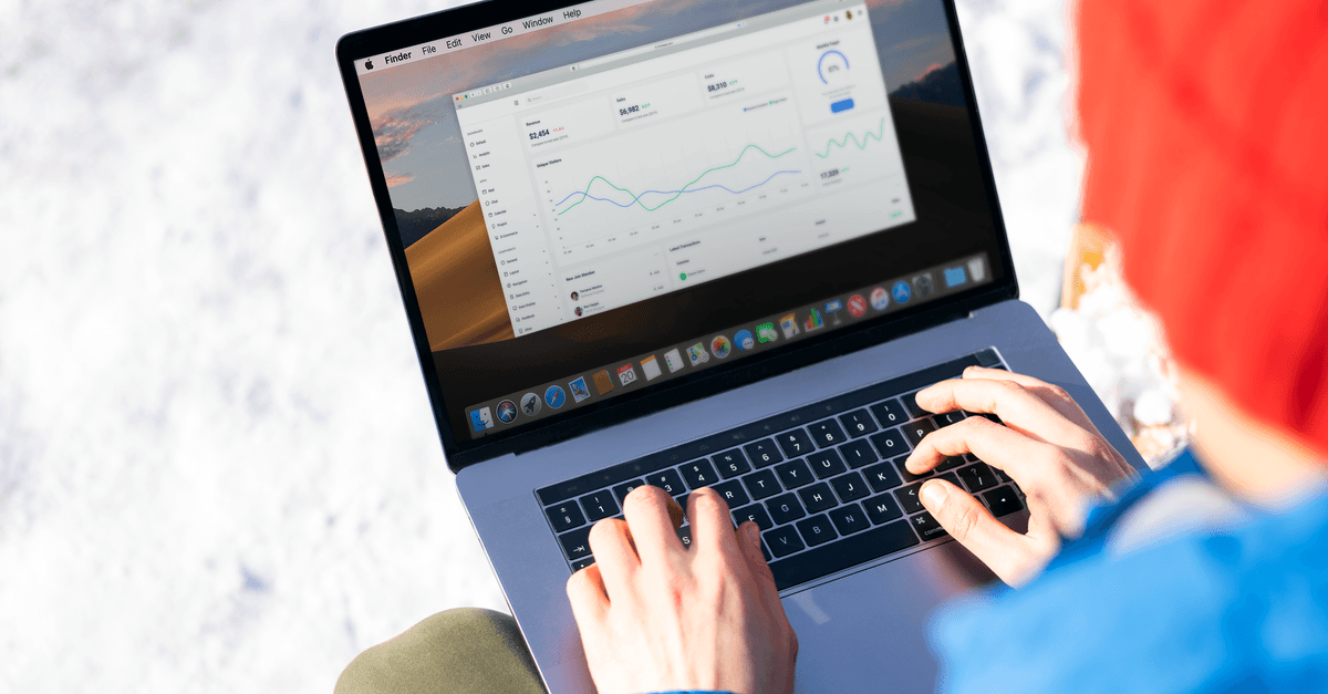 Person in blauer Jacke analysiert im Winter draußen Geschäftsdaten auf einem Laptop