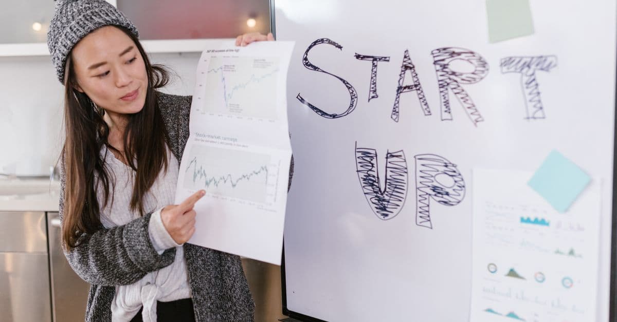 Asiatische Frau präsentiert bei einem Startup-Pitch Wachstumsdiagramme in einem Innenraum.