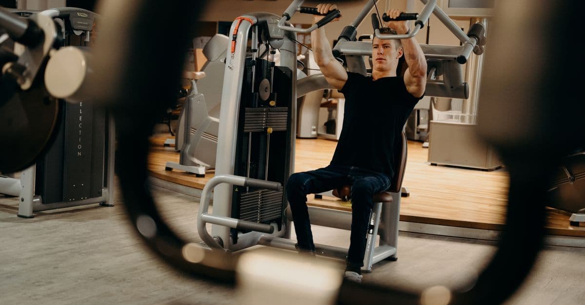 A man working out on a gym machine, focusing on upper body strength training.