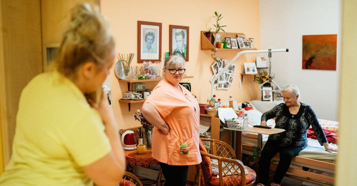 Caregivers interacting with a senior woman in a cozy retirement home in Karviná, Czech Republic.