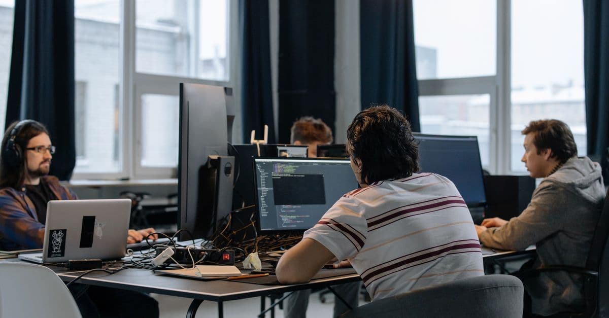 Entwicklerteam arbeitet gemeinsam an Computern in einem modernen Tech-Büro.