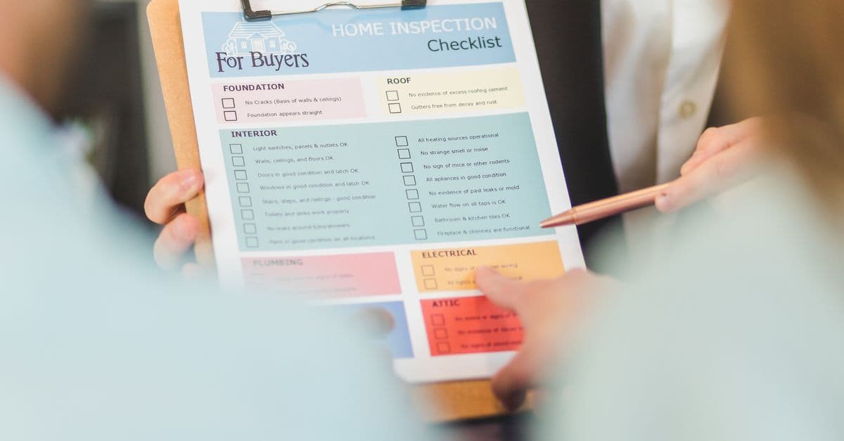 Close-up of hands holding a home inspection checklist clipboard for buyers.