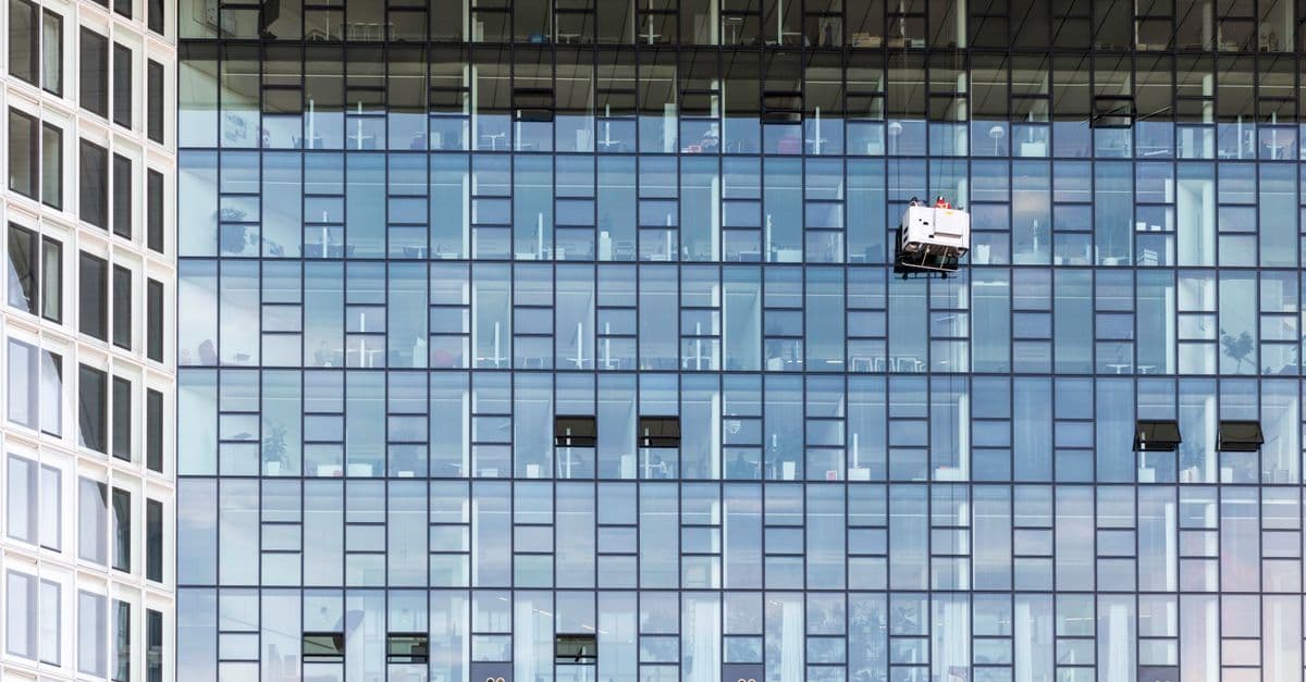 Reinigungskraft mit professioneller Ausrüstung startet den ersten Auftrag in einem Bürogebäude