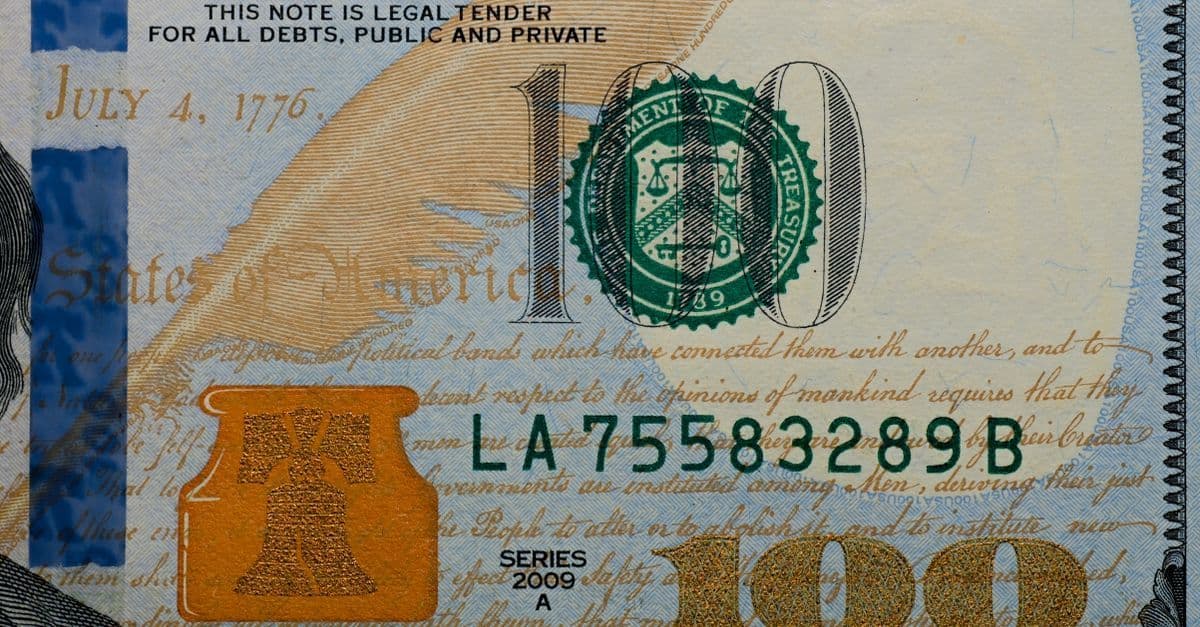 Detailed view of a US 100 dollar bill highlighting security features and design elements.