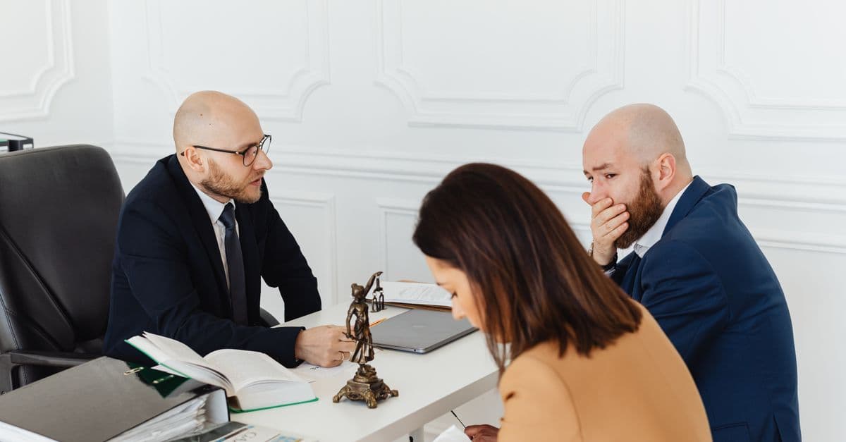 Drei Erwachsene bei ernstem Beratungsgespräch in einem professionellen Büro.