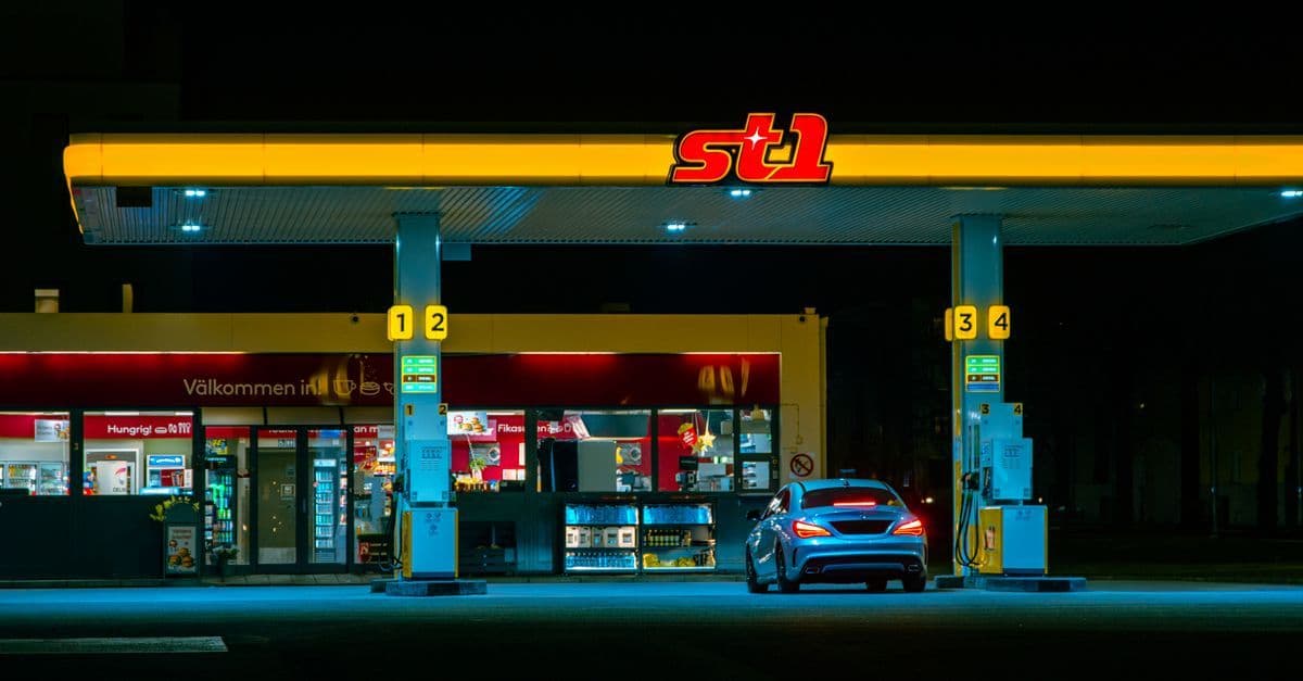 A car refuels at the illuminated St1 gas station in Jönköping, Sweden at night.