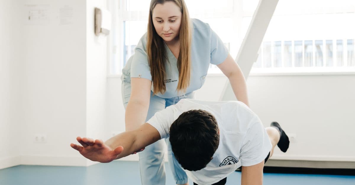 A physiotherapist assists a patient in stretching exercises indoors.