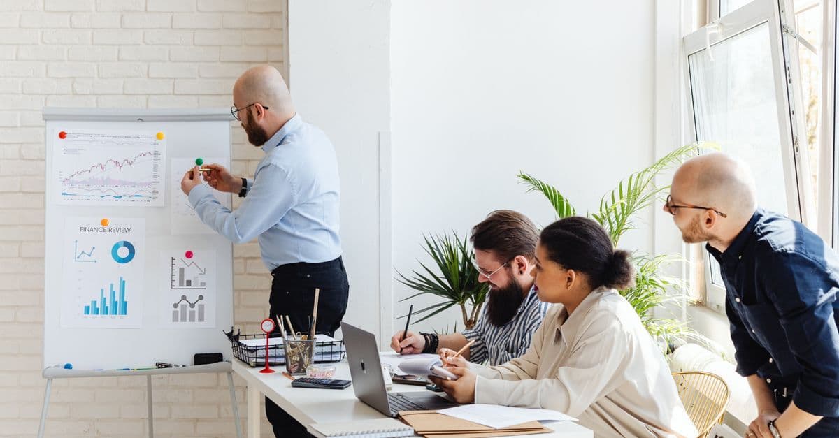 Diverse Fachleute besprechen Finanzdaten in einem modernen Büro vor Laptop und Unterlagen.