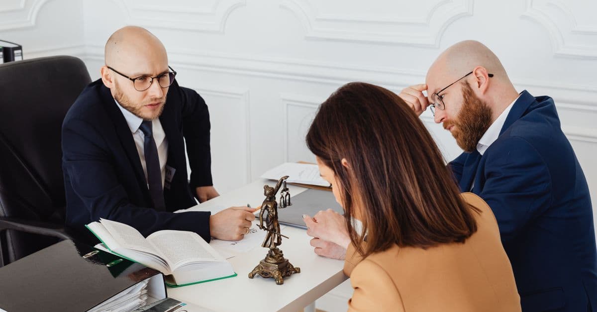 Anwalt bespricht in modernem Büro ernsthaft Unterlagen mit Mandanten