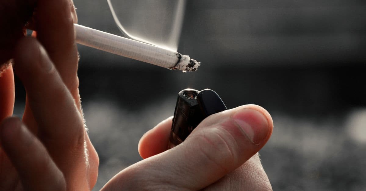 Detailed image of hands holding a cigarette and lighter, emphasizing smoking habit.