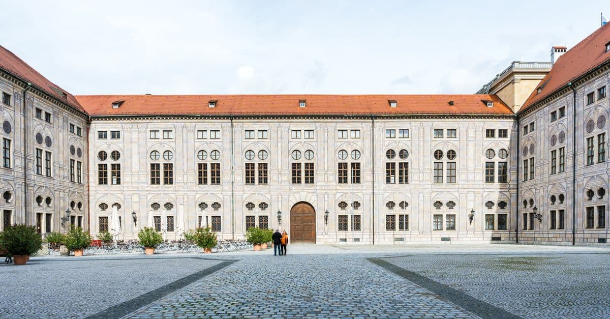 Exterior view of a historic baroque palace courtyard with cobblestone paving and elegant facade.